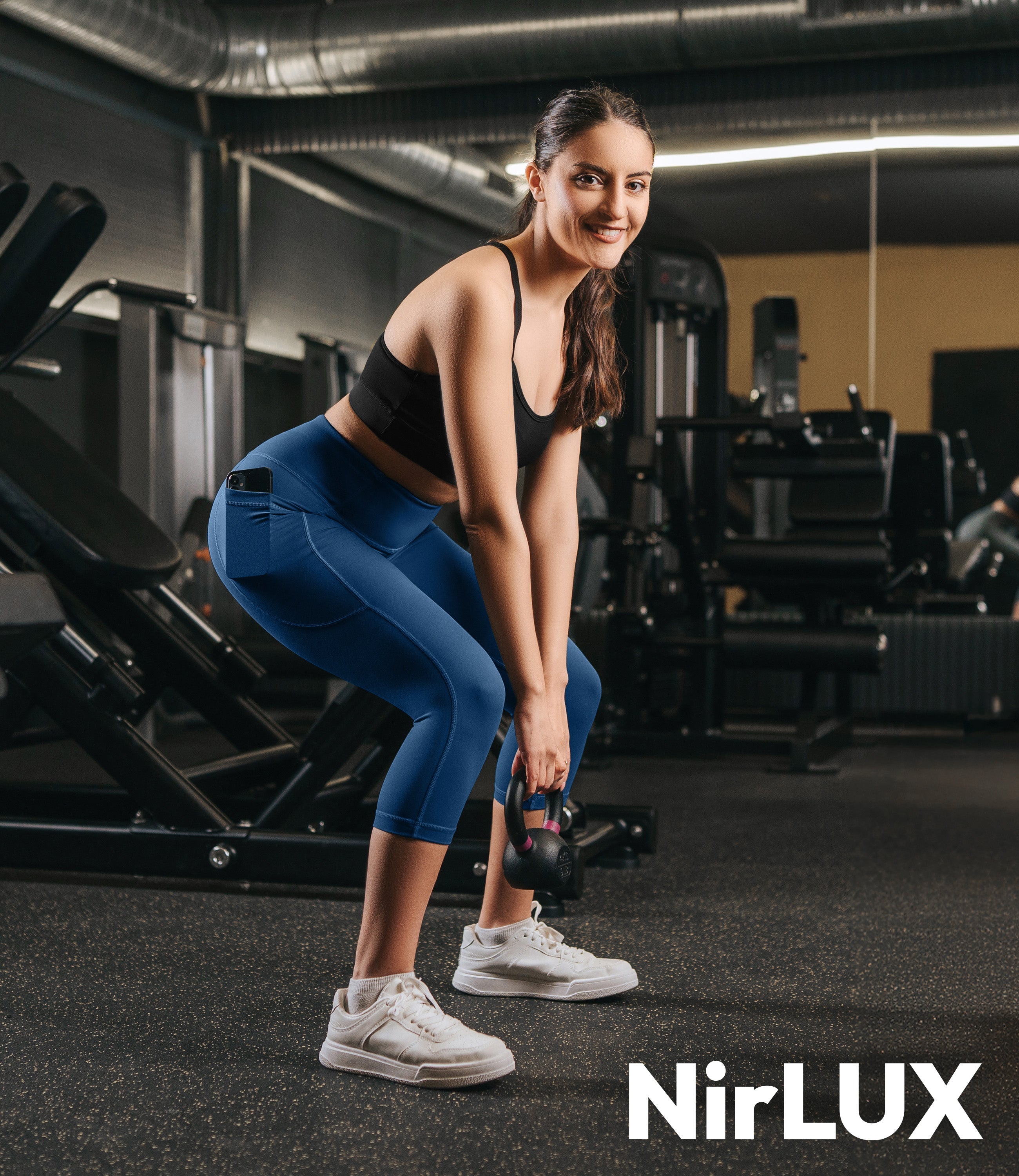 Woman wearing NirLUX women's workout capris in limoges navy, while working out, showcasing all-day comfort