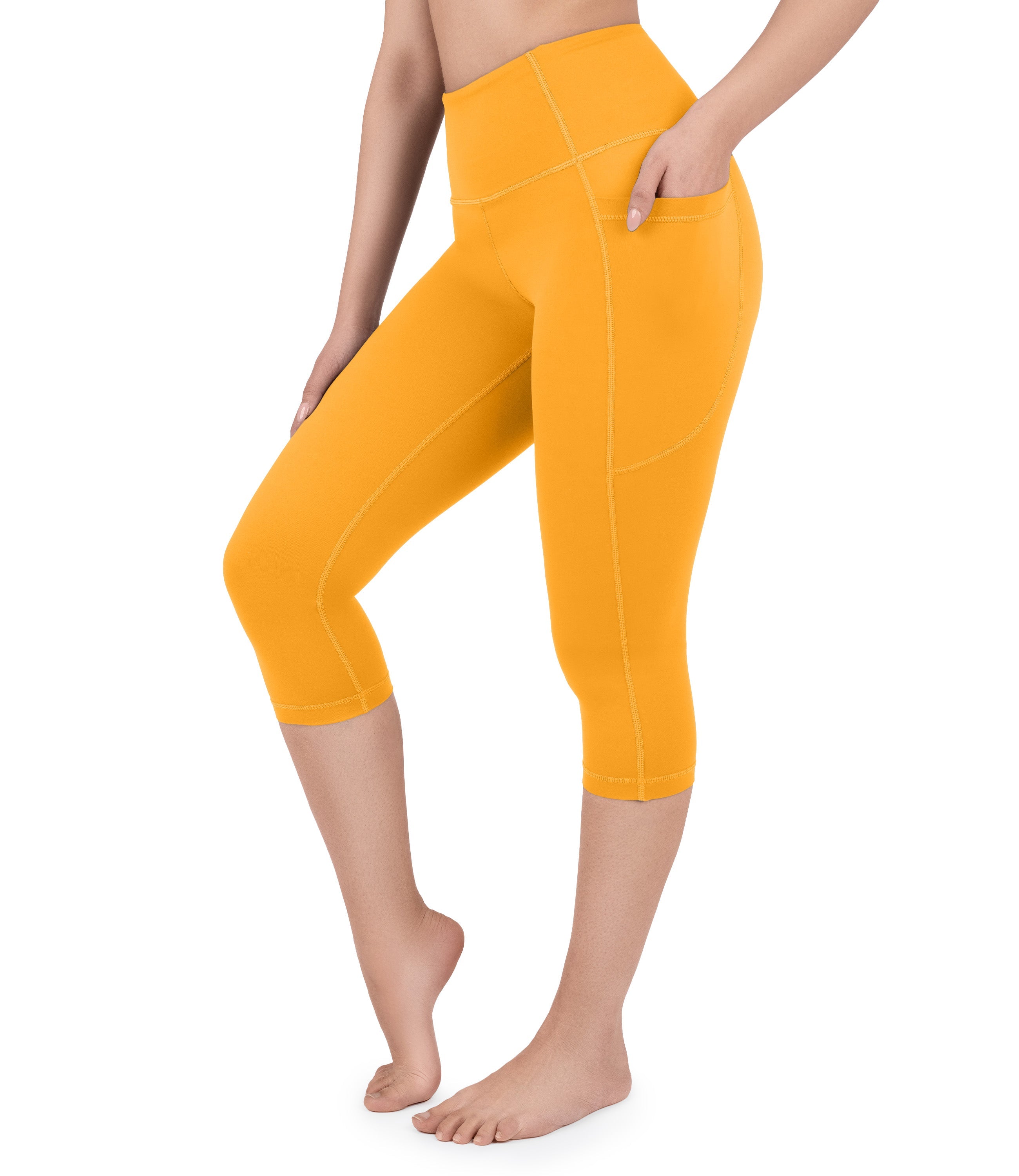 Front view of woman wearing NirLUX capri leggings with pockets in bright marigold
