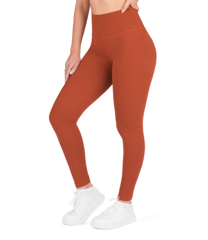 Front view of woman wearing NirLUX high waist ankle leggings in intense rust